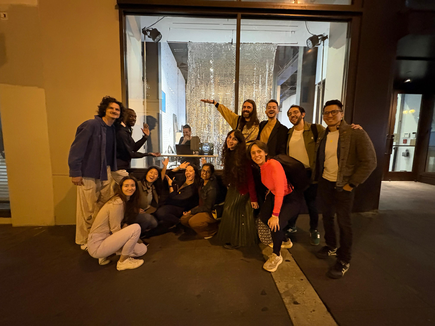Group photo of performers and audience outside the venue at night